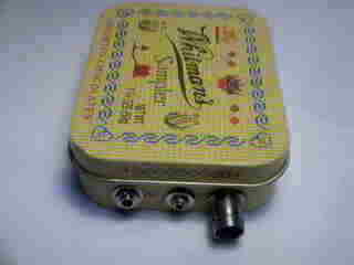 pixie in a small candy tin showing key, earphone and antenna jacks, battery inside, no power switch used.